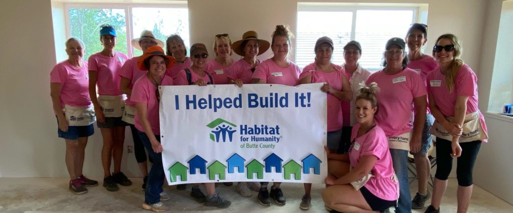 A group of volunteers posing together and holding a sign that says, "I Helped Build It."