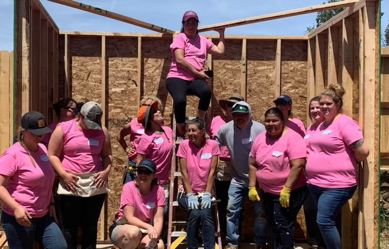 Volunteers posing as a group in front of a construction in progress.