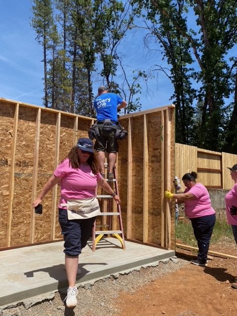 Volunteers working together to build the wall of a house.