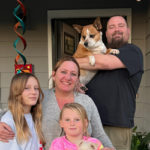 Kayla, her family, and pet dog standing in front of their new home.