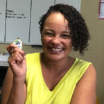 Ruby, smiling and holding something with the Habitat for Humanity logo. 